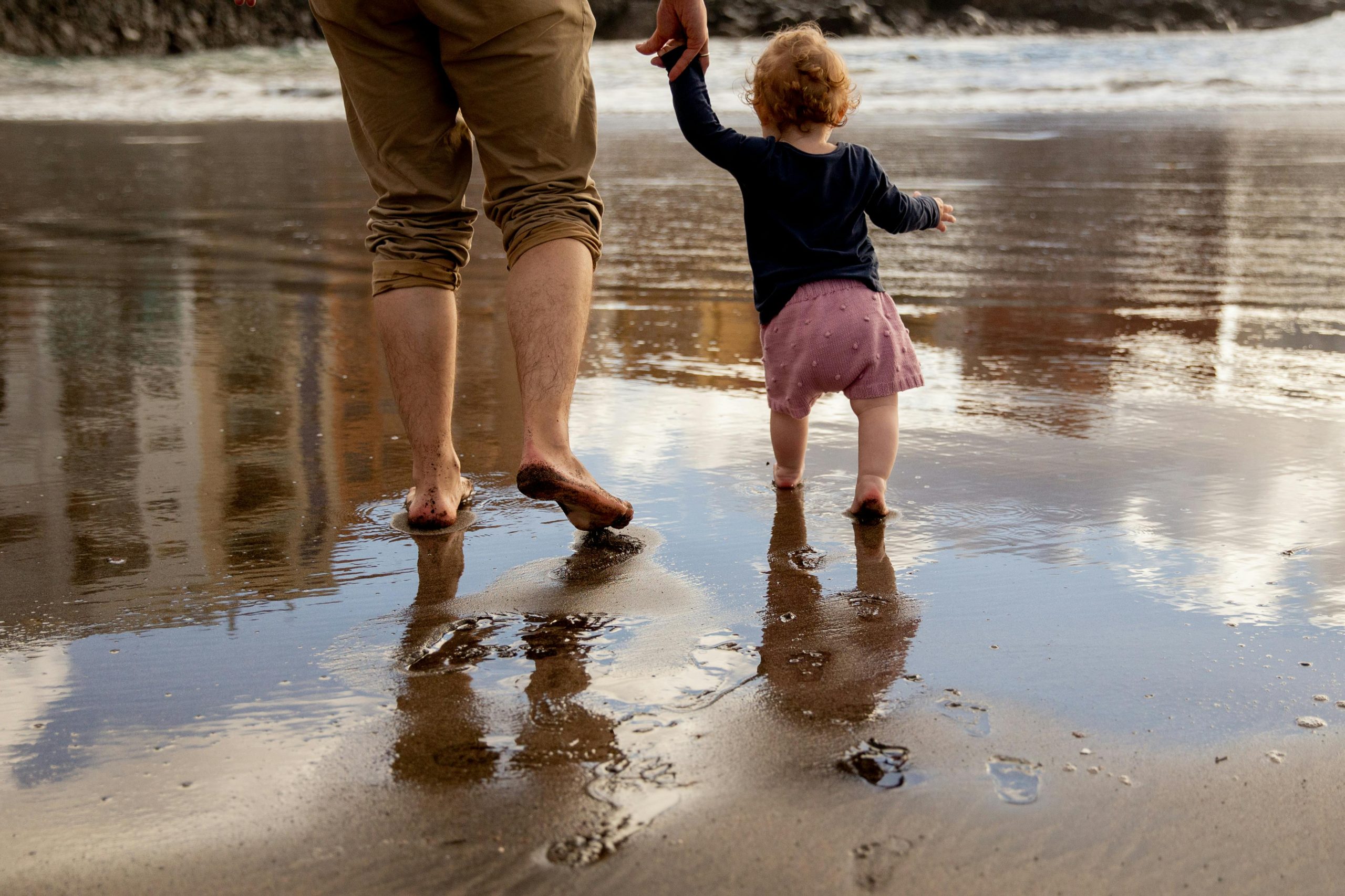 Father and child walking on shore of water