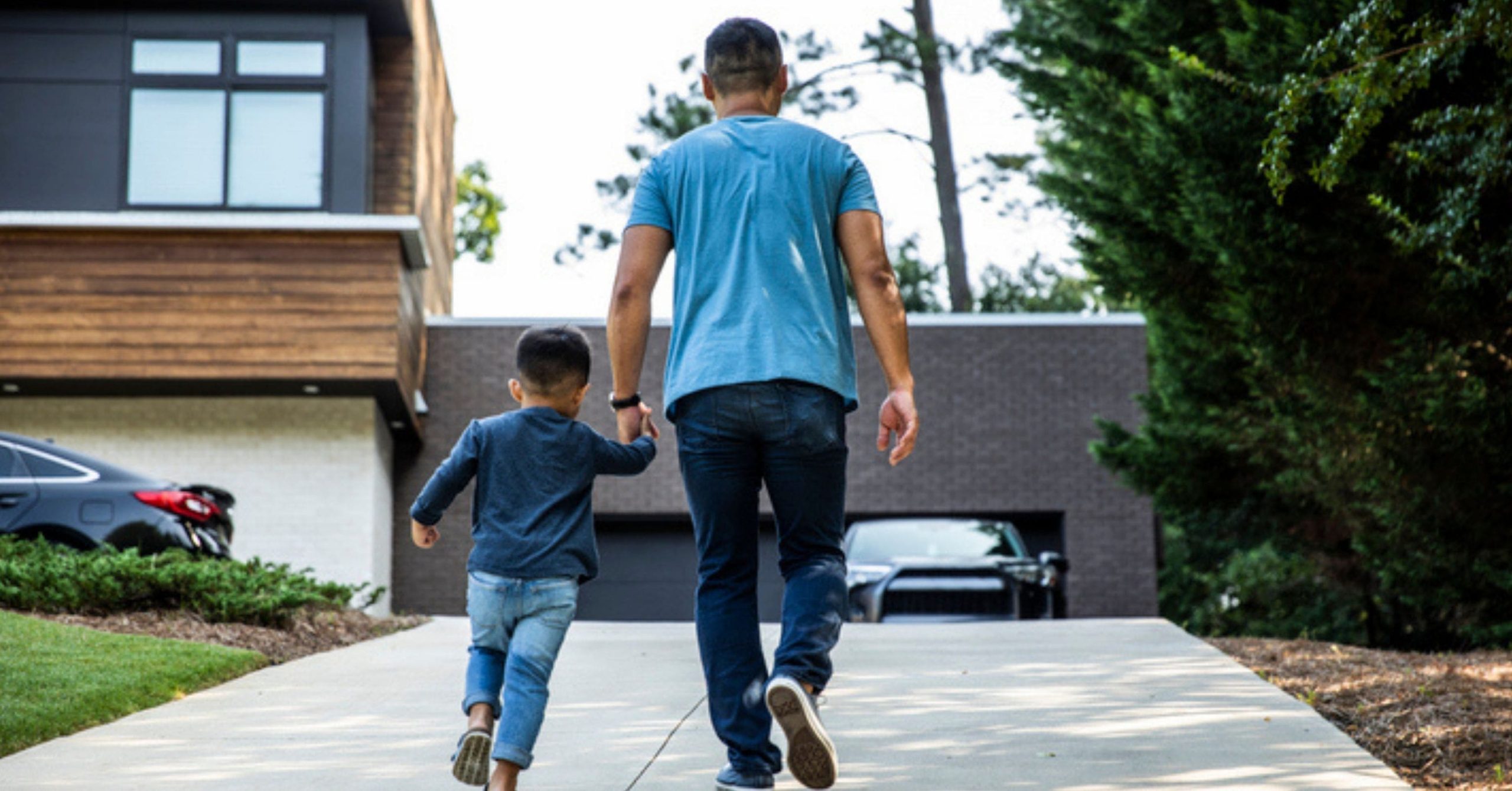 Father walking up driveway to a house with son